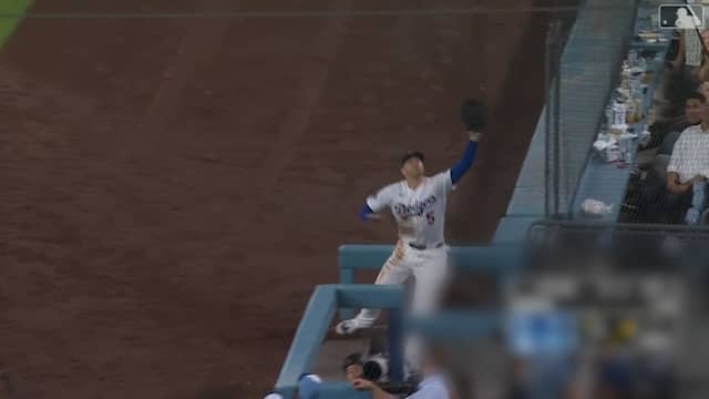 Honkballer probeert bal te vangen en valt in dug-out