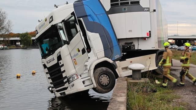 Vrachtwagencabine bungelt net boven het water in Badhoevedorp