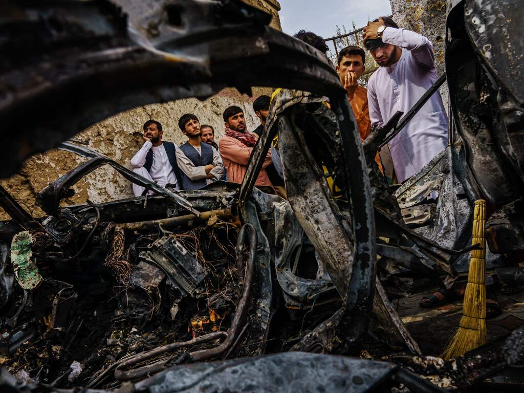 Afghanen bekijken in de Afghaanse hoofdstad Kaboel het wrak van een auto die werd verwoest door een Amerikaanse droneaanval. Bij de aanval kwamen tien mensen, onder wie enkele kinderen, om het leven.