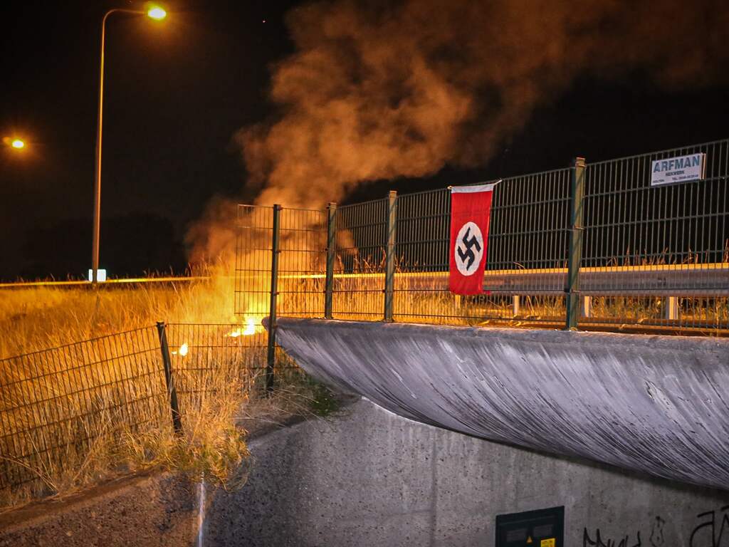 Politie onderzoekt bij bermbrand langs A1 opgehangen nazivlag