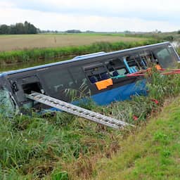 Video | Lijnbus ligt in kanaal na botsing met motorrijder in Friesland