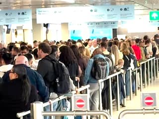 Reizigers wachten in lange rijen door storing bij poortjes op Schiphol
