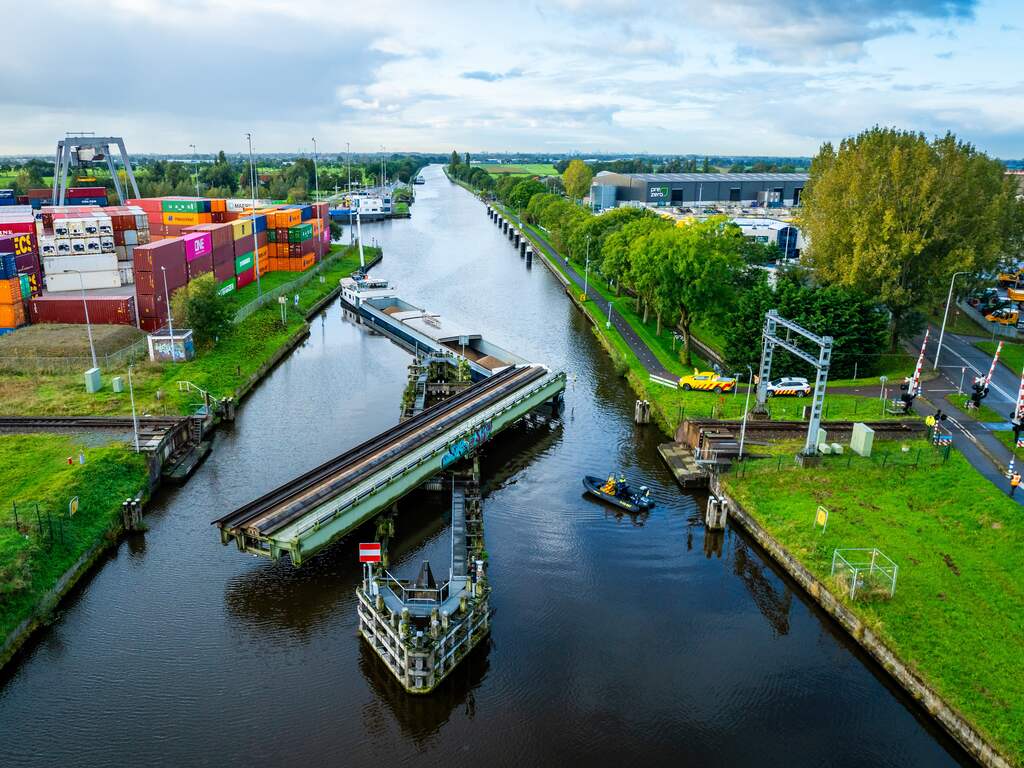 Schip ligt klem onder spoorbrug Alphen aan den Rijn na aanvaring, geen treinen