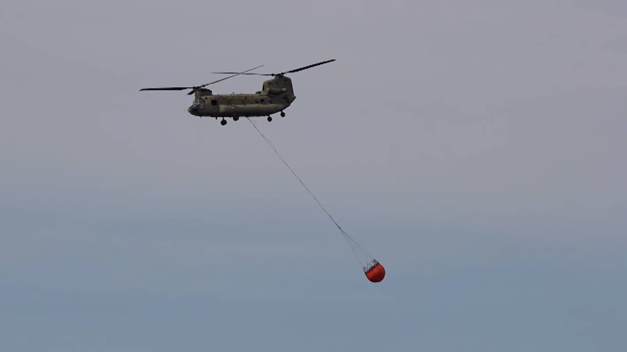 Chinook vliegt af en aan met water om bosbrand in Limburg te blussen