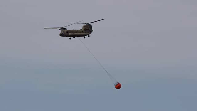 Chinook vliegt af en aan met water om bosbrand in Limburg te blussen