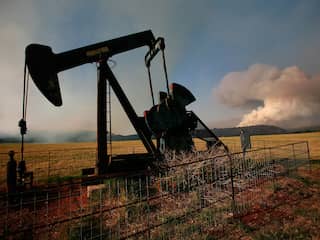 Olieproductie in Texas, terwijl op de achtergrond een bosbrand woedt