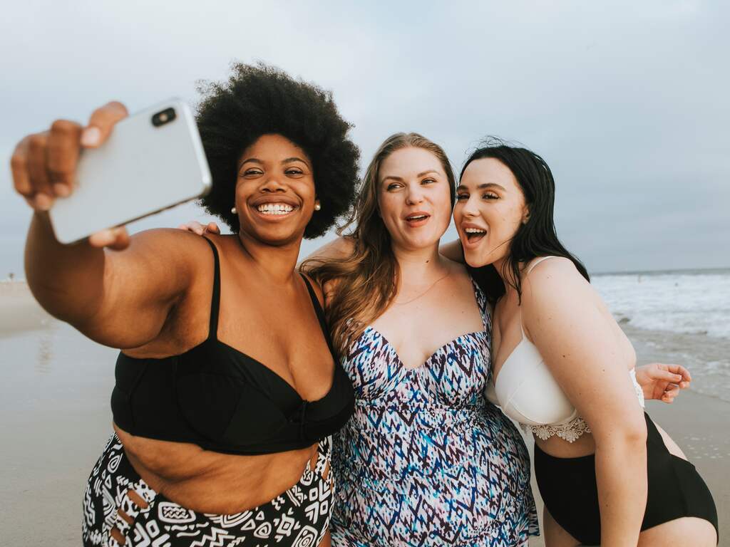 Vrouwen met smartphone maken selfie op het strand