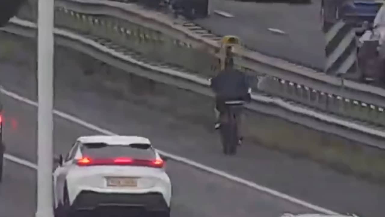 Fatbiker rijdt tussen druk verkeer op vluchtstrook A16 bij Rotterdam