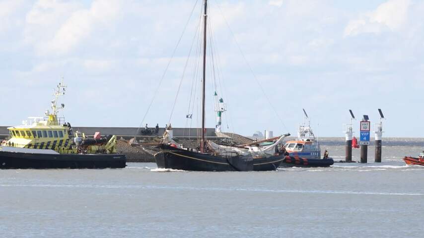 Zeilschip met afgebroken giek vaart haven Harlingen binnen